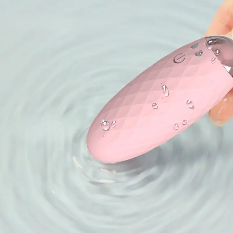 Œuf vibreur Doris rose waterproof en silicone texturé, tenu en main et immergé dans l'eau.