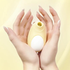 Stimulateur Penguin jaune tenu délicatement entre deux mains féminines