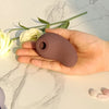 Stimulateur Virgule marron vu de face dans une main