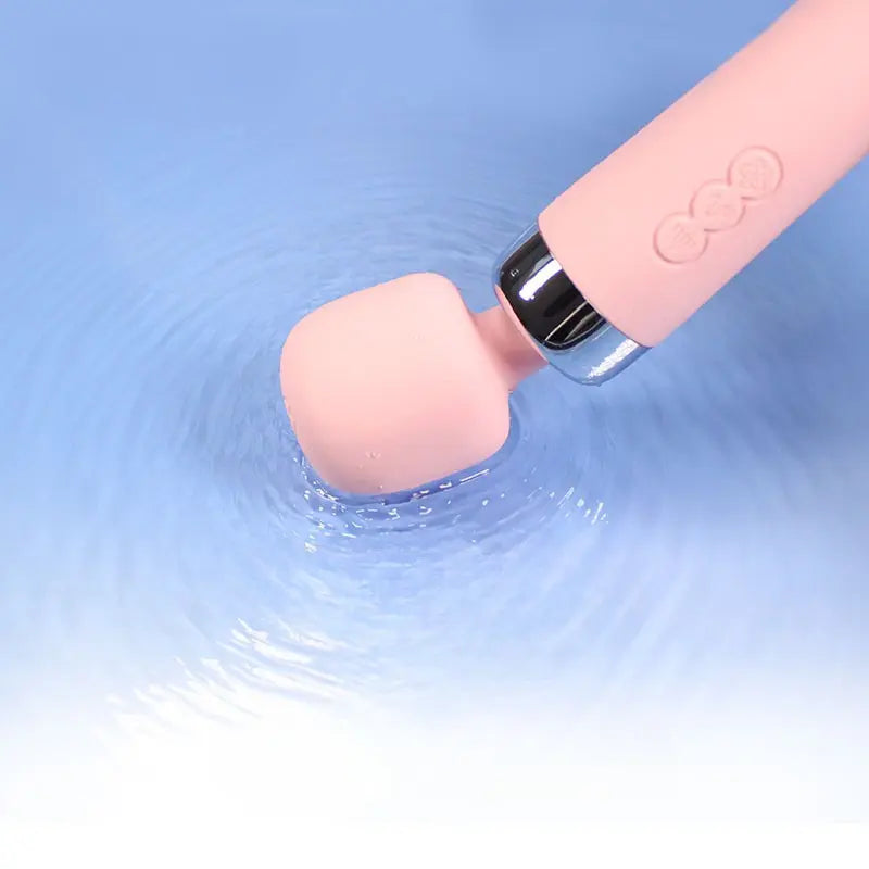 Gros plan sur la tête du wand masseur Sakura rose, en pleine vibration dans l’eau