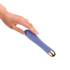 Vibromasseur double moteur tenu en main, montrant sa prise ergonomique et sa finition soignée.